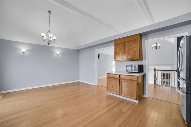 kitchen with a chandelier, light wood-style floors, freestanding refrigerator, and vaulted ceiling with beams