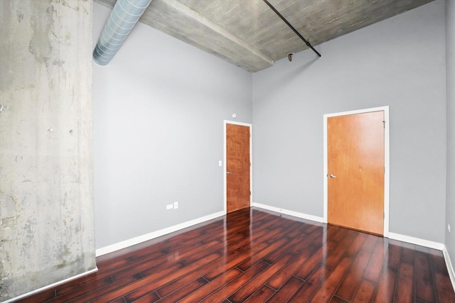 spare room featuring a high ceiling, wood finished floors, and baseboards