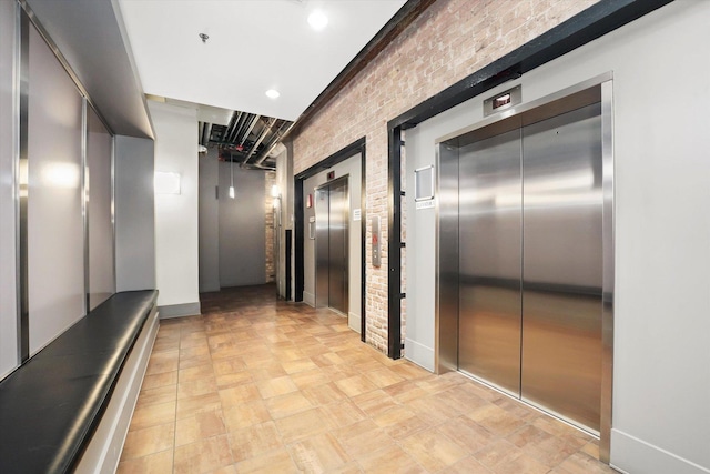 hall featuring brick wall and elevator