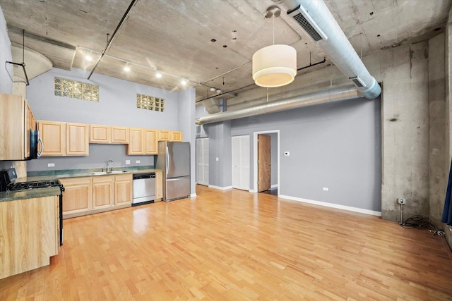 kitchen with visible vents, a towering ceiling, appliances with stainless steel finishes, light brown cabinetry, and light wood-type flooring