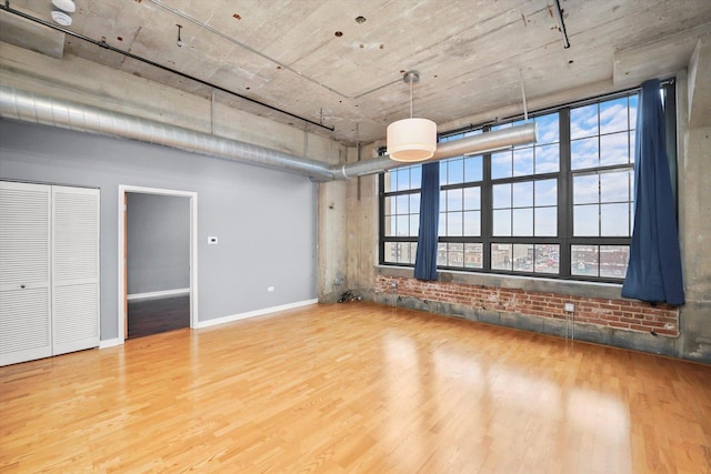 interior space with brick wall, baseboards, and wood finished floors