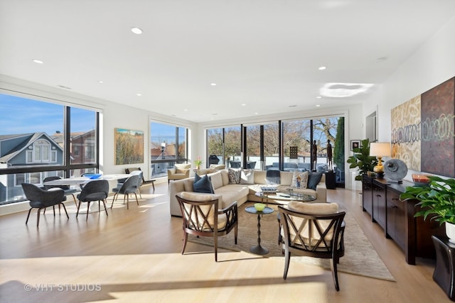 living area with a wealth of natural light, light wood finished floors, and recessed lighting