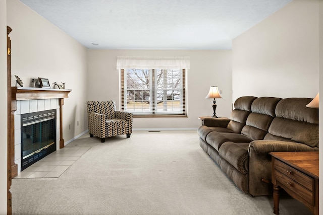 living area featuring a tile fireplace, light carpet, visible vents, and baseboards