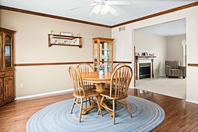 dining room with light wood-type flooring, a tile fireplace, visible vents, and baseboards