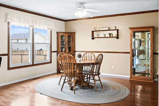 dining space featuring baseboards, visible vents, a ceiling fan, ornamental molding, and hardwood / wood-style floors