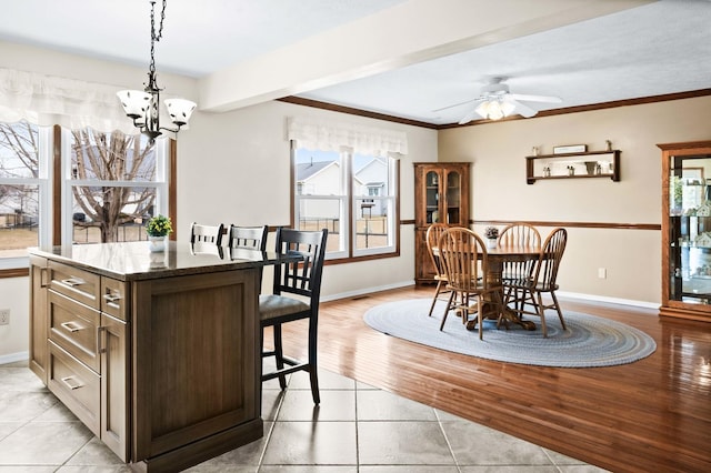 dining area with ornamental molding, light wood-type flooring, baseboards, and ceiling fan with notable chandelier