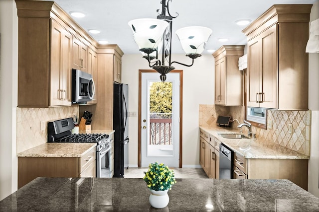 kitchen with stone counters, stainless steel appliances, a sink, tasteful backsplash, and decorative light fixtures