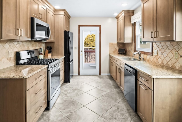 kitchen featuring appliances with stainless steel finishes, plenty of natural light, a sink, and light stone countertops