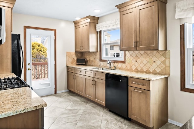 kitchen with a healthy amount of sunlight, black appliances, decorative backsplash, and a sink