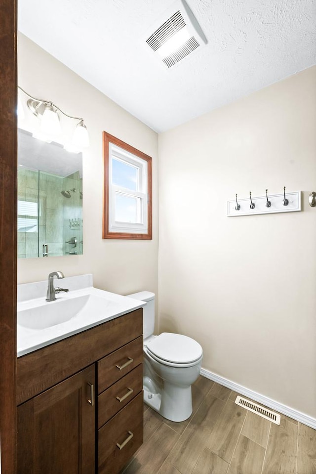 bathroom featuring toilet, wood finished floors, a shower stall, and visible vents