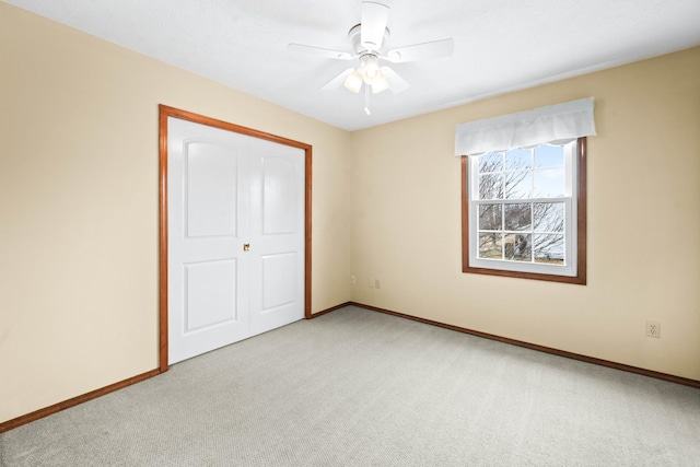 unfurnished bedroom with baseboards, a closet, a ceiling fan, and light colored carpet