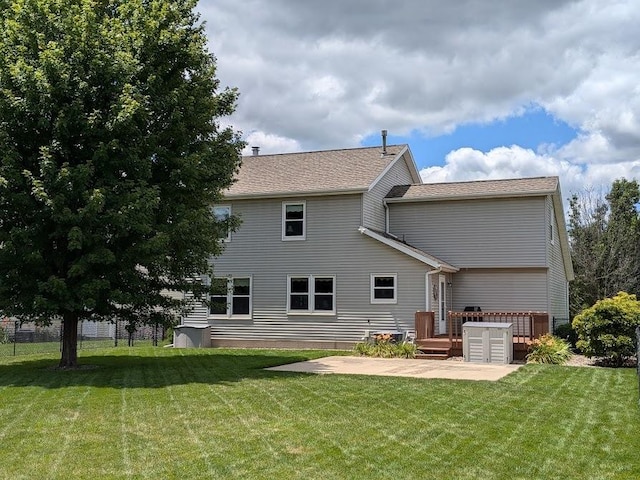 rear view of house featuring a lawn, fence, a wooden deck, and a patio