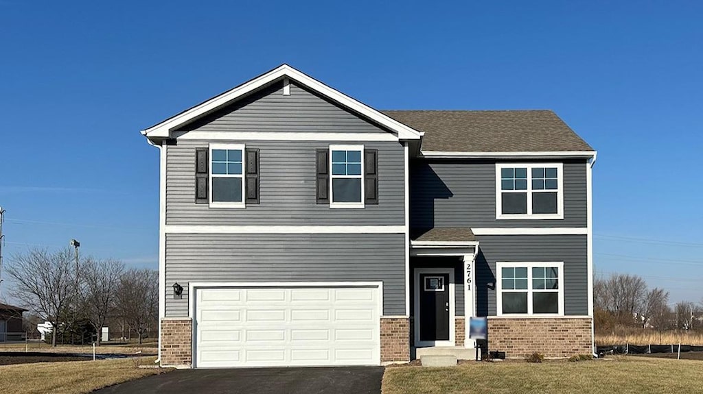 view of front of property with an attached garage, a front yard, aphalt driveway, and brick siding