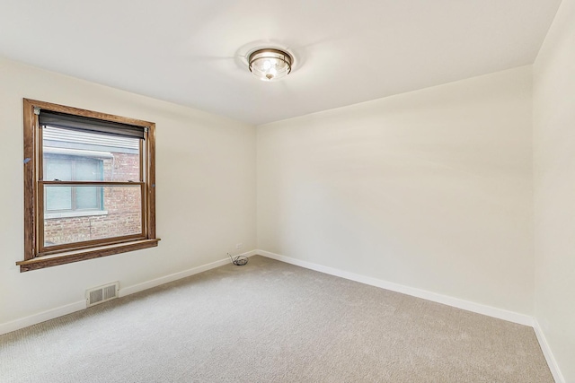 spare room with visible vents, light carpet, and baseboards