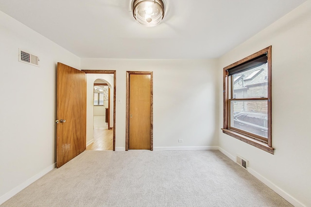 unfurnished bedroom with light carpet, visible vents, and multiple windows