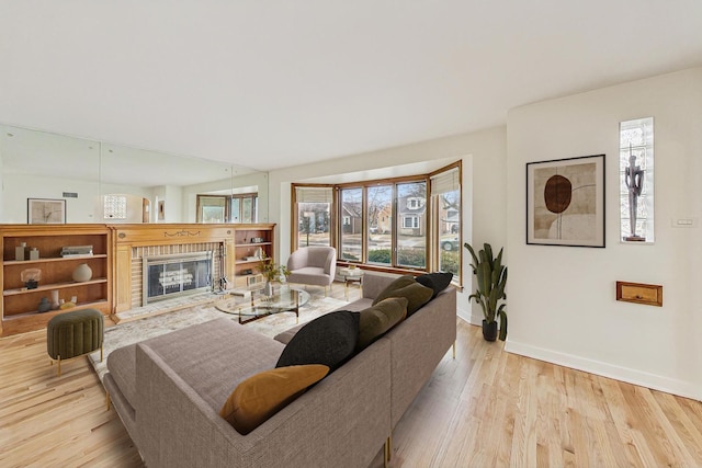 living area featuring a fireplace, wood finished floors, and baseboards