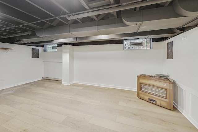 basement featuring electric panel, a baseboard heating unit, heating unit, and wood finished floors