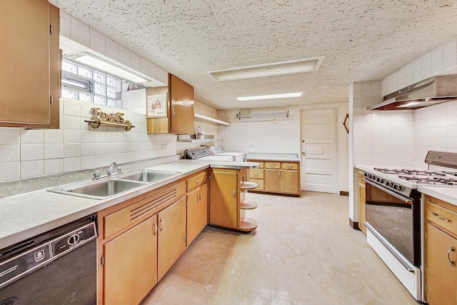 kitchen featuring washing machine and clothes dryer, gas range gas stove, dishwasher, light countertops, and a sink