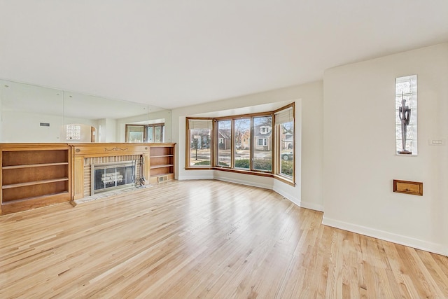 unfurnished living room with baseboards, light wood-style floors, and a fireplace