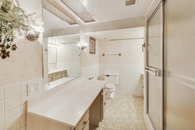 bathroom with visible vents, wallpapered walls, tile walls, a shower stall, and wainscoting