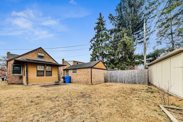 back of property featuring a yard, an outbuilding, brick siding, and fence