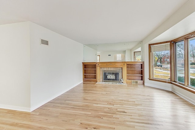 unfurnished living room featuring visible vents, baseboards, a brick fireplace, and light wood finished floors