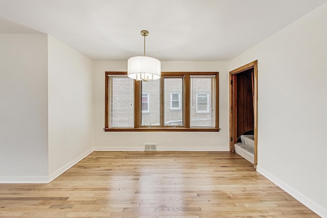 unfurnished dining area with visible vents, baseboards, light wood-style floors, and stairs