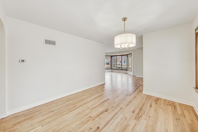 spare room with light wood-style floors, visible vents, and baseboards