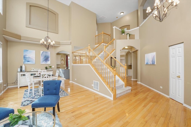 foyer entrance featuring visible vents, arched walkways, wood finished floors, stairs, and a chandelier