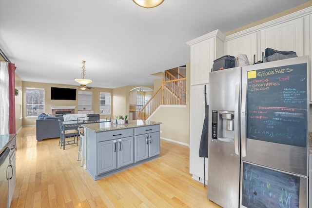 kitchen with appliances with stainless steel finishes, a center island, gray cabinets, light wood-type flooring, and a fireplace