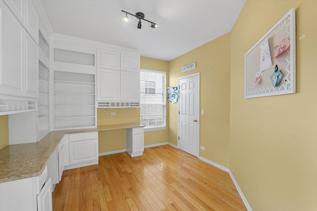 kitchen featuring light wood-type flooring, white cabinets, built in study area, and open shelves