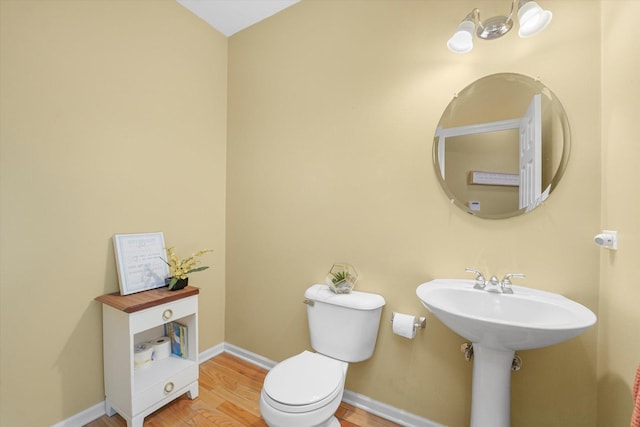 half bathroom featuring toilet, baseboards, and wood finished floors