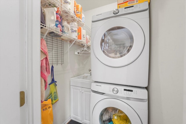 laundry room featuring stacked washer and clothes dryer and cabinet space