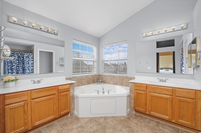 bathroom featuring lofted ceiling, two vanities, a sink, and a bath