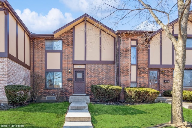 view of front of property featuring brick siding, stucco siding, and a front lawn