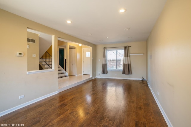 unfurnished room featuring recessed lighting, baseboards, wood finished floors, and stairs