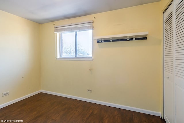 spare room featuring baseboards and dark wood finished floors