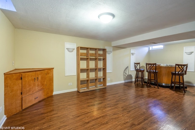 interior space with a dry bar, wood finished floors, baseboards, and a textured ceiling