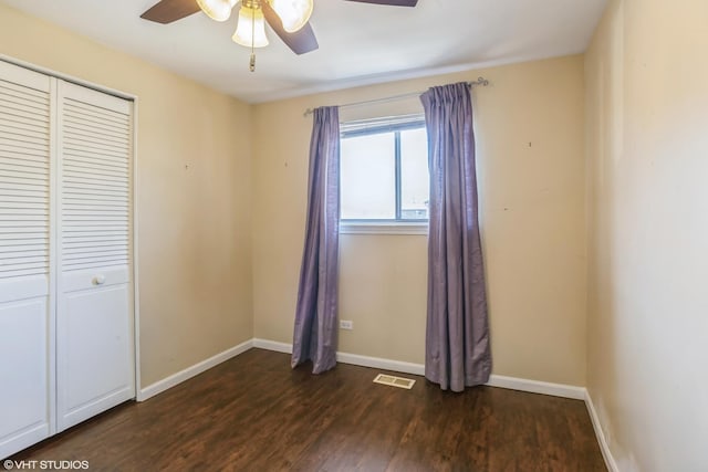 unfurnished bedroom with visible vents, baseboards, a closet, a ceiling fan, and dark wood-style flooring