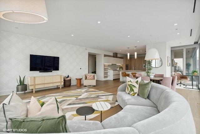 living room featuring an accent wall, recessed lighting, and wallpapered walls