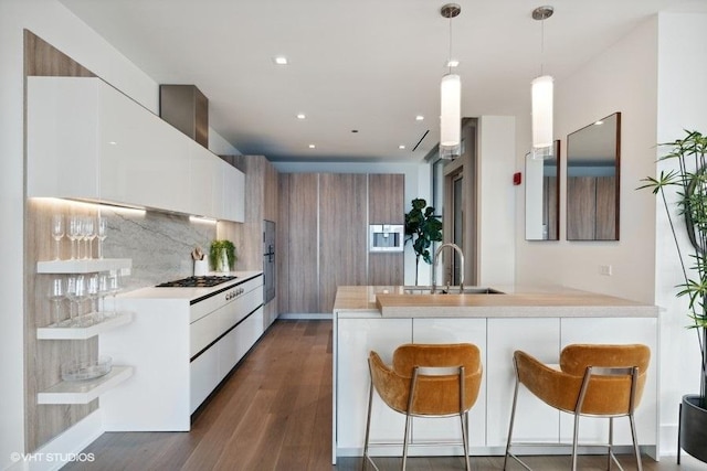 kitchen featuring dark wood-style flooring, light countertops, a sink, modern cabinets, and a peninsula