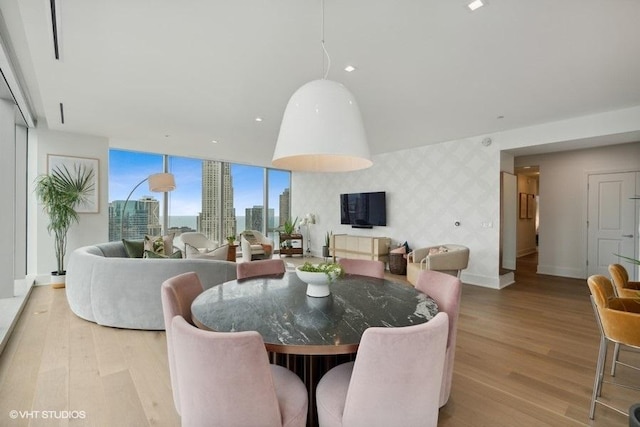 dining area featuring an accent wall, light wood-style flooring, baseboards, and wallpapered walls