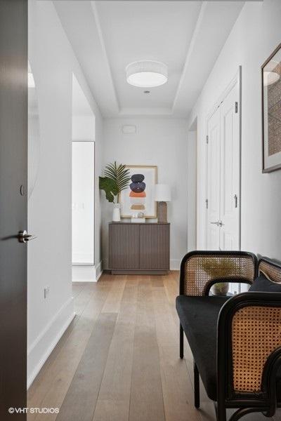 sitting room featuring a tray ceiling, baseboards, and wood finished floors