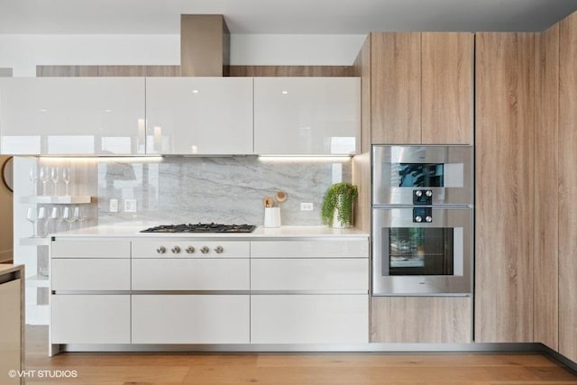 kitchen featuring stainless steel double oven, gas stovetop, light countertops, tasteful backsplash, and modern cabinets