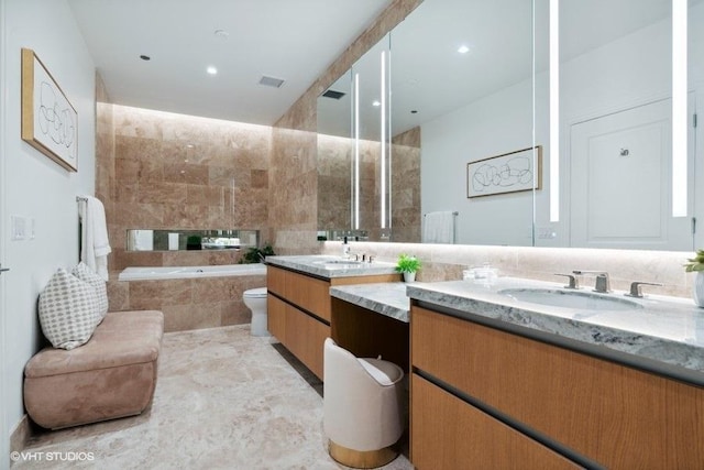 bathroom featuring tiled tub, visible vents, and vanity