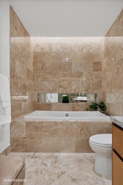 full bathroom featuring toilet, a garden tub, tile walls, and vanity