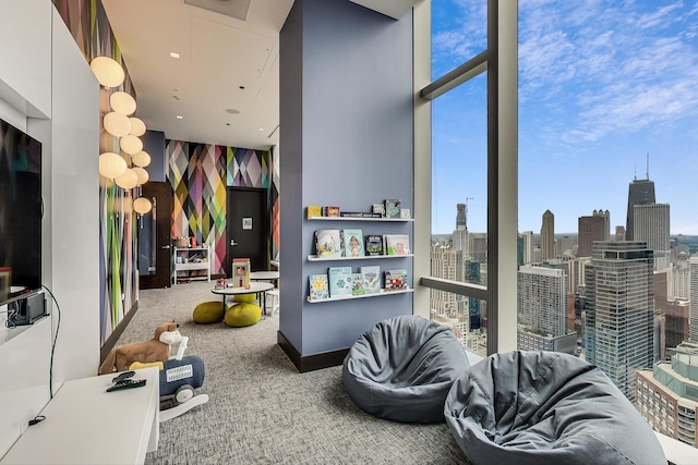 recreation room featuring a view of city, carpet, expansive windows, and baseboards