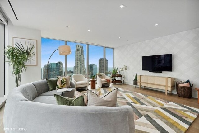 living room with recessed lighting, wood finished floors, baseboards, floor to ceiling windows, and wallpapered walls