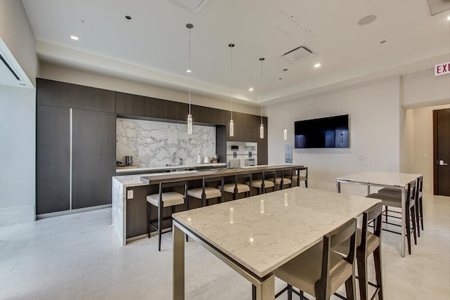 kitchen with a breakfast bar, pendant lighting, a large island, tasteful backsplash, and modern cabinets