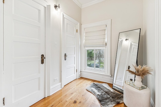 entryway with light wood-style flooring, baseboards, and ornamental molding